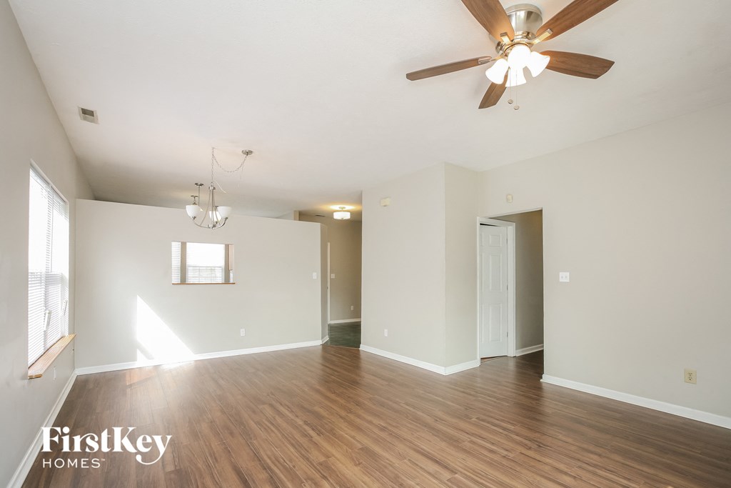 an empty living room with wood floors and a ceiling fan