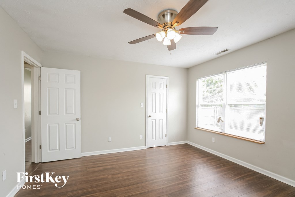 an empty living room with a ceiling fan and a window