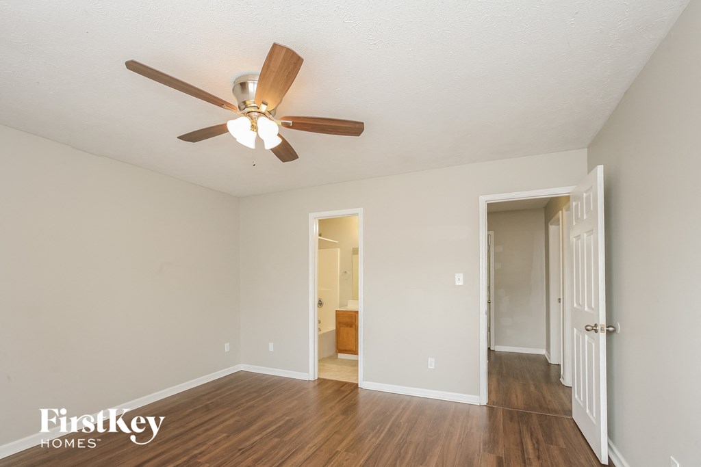 a living room with a ceiling fan and a door to a hallway