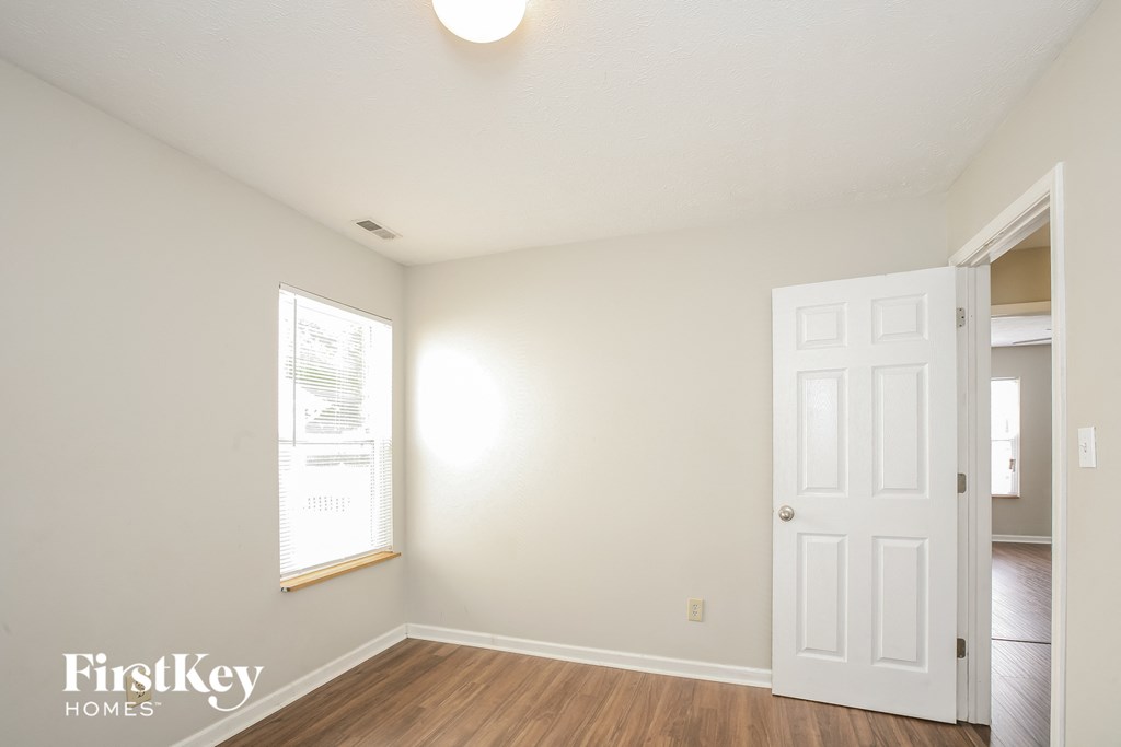 a bedroom with white walls and a white door and wood floors