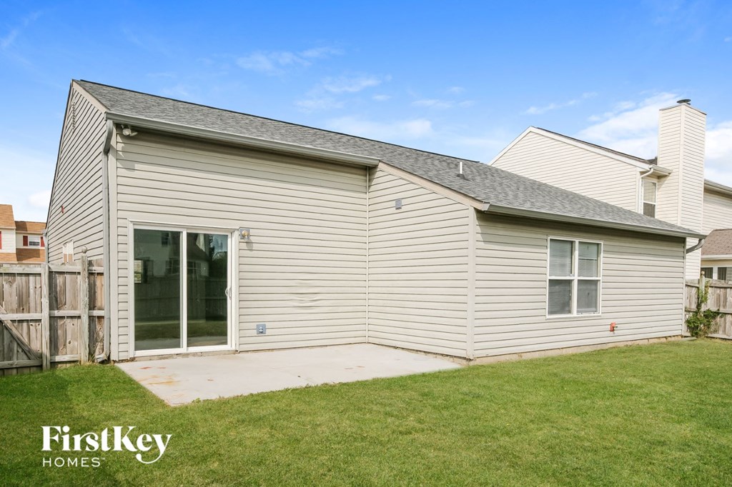 the outside of a white house with a yard and a backdoor