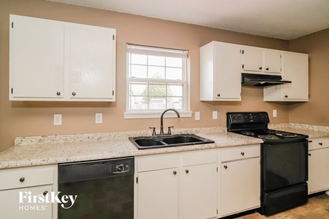 A kitchen with white cabinets and a black stove top oven.