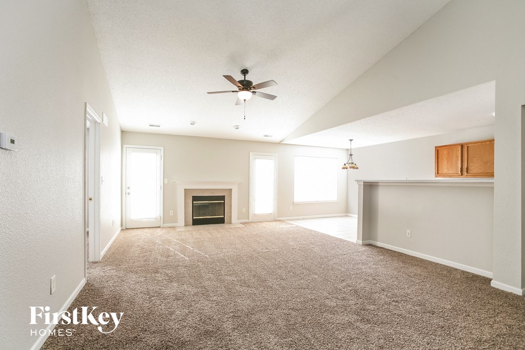 A spacious living room with a fireplace and a ceiling fan.