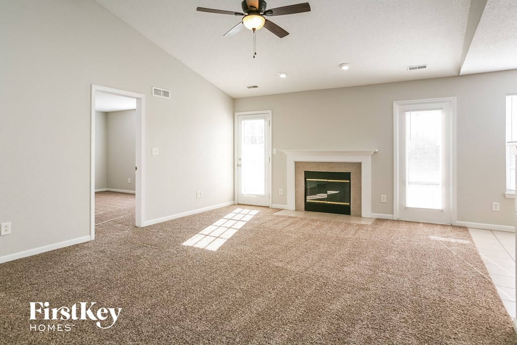 A spacious room with a fireplace and a carpeted floor.