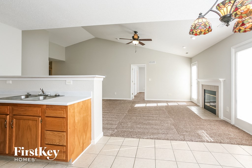 A spacious living room with a kitchen area and a fireplace.