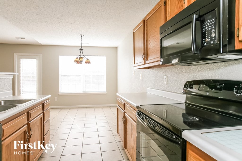 A kitchen with a black microwave and stove top oven.