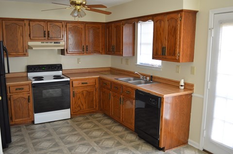 A kitchen with wooden cabinets and black appliances.