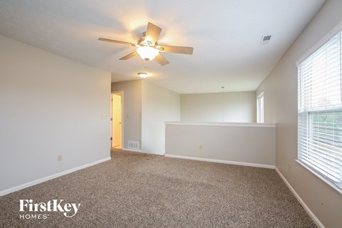 A spacious room with a ceiling fan and carpeted floor.
