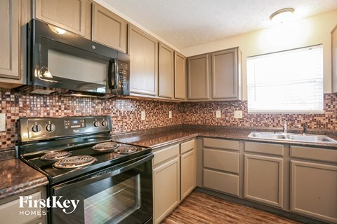 A kitchen with a black stove and a black microwave above it.