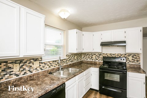 A kitchen with white cabinets and a black stove top oven.