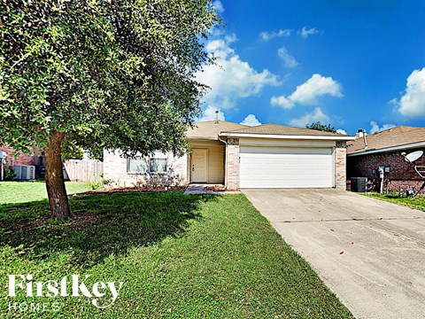 the front of a house with a driveway and a tree