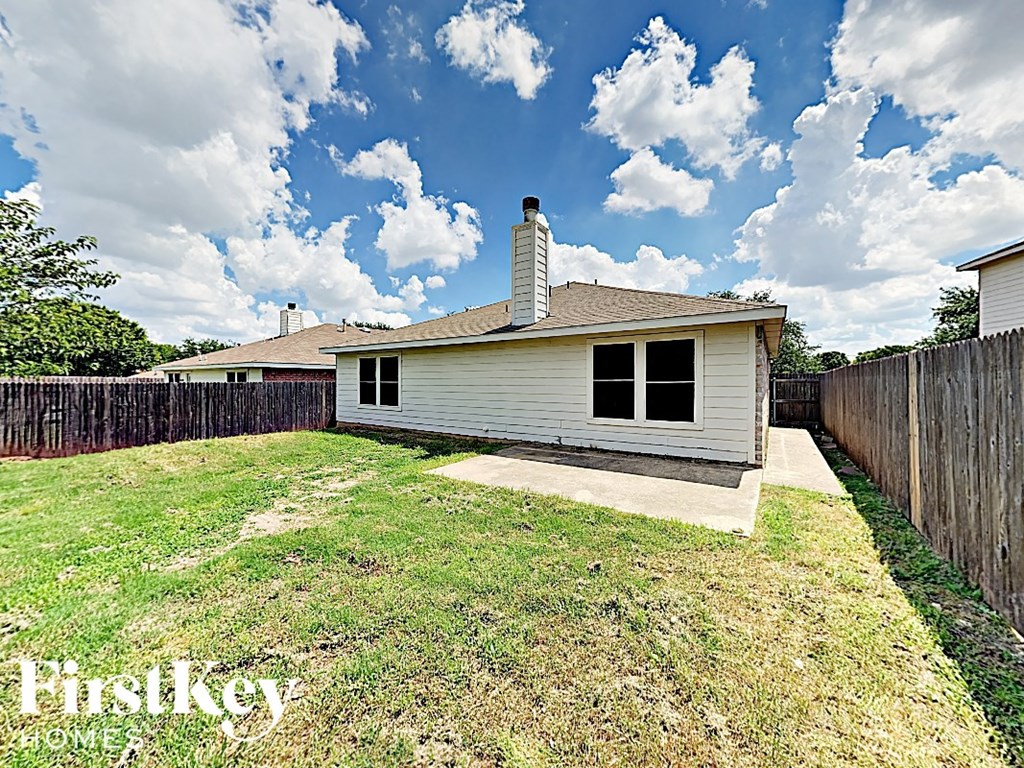 a small white house with a yard and a fence