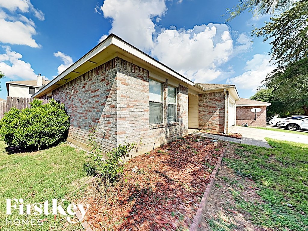 a brick house with a yard and a cloudy sky