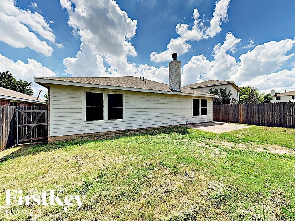 a small white house with a yard and a fence