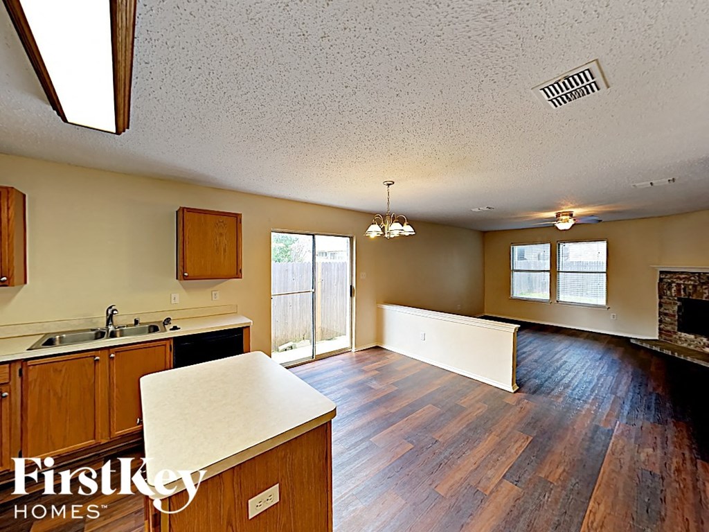 an empty kitchen and living room with a fireplace and wood floors