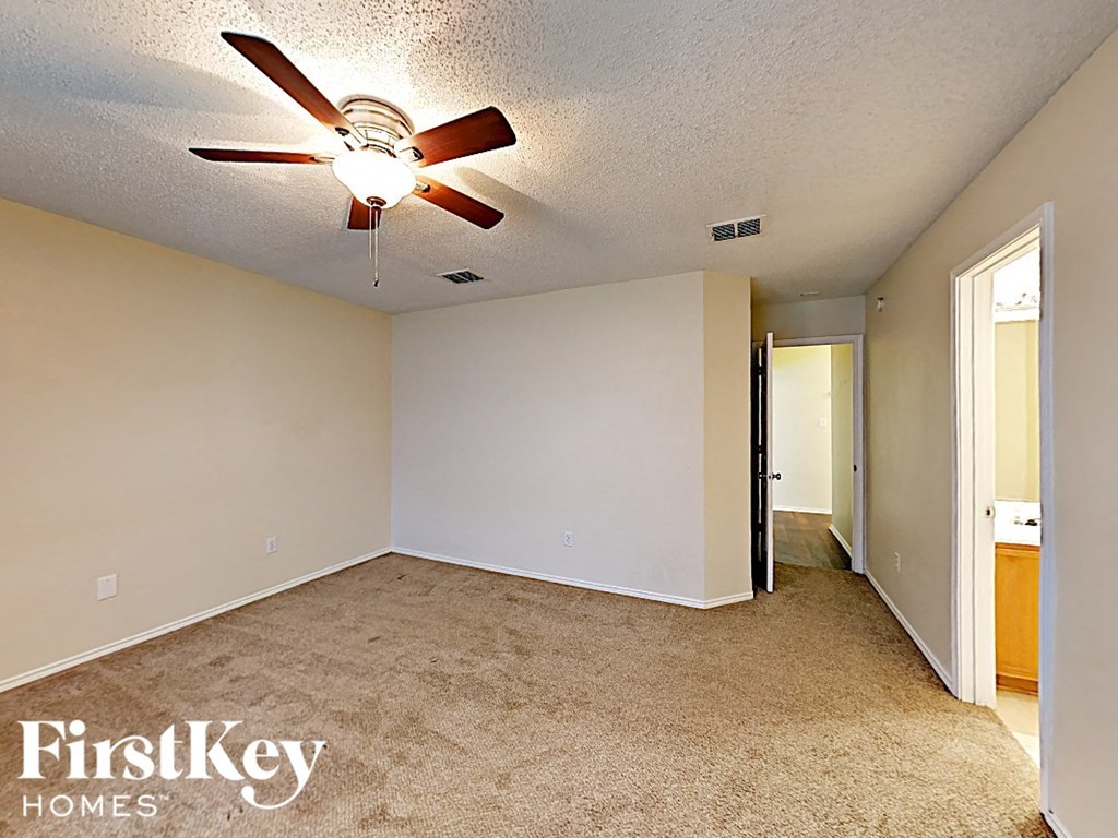 an empty living room with a ceiling fan