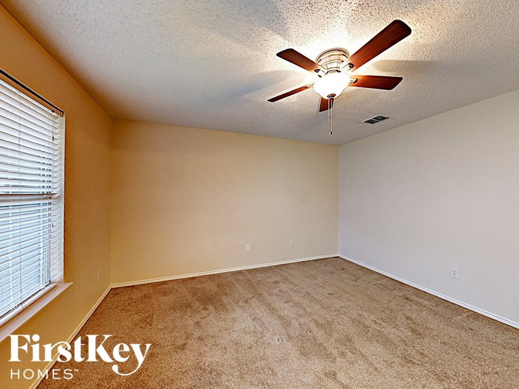 an empty bedroom with a ceiling fan and a window