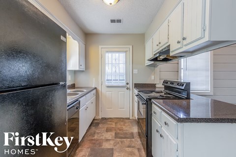 A kitchen with a black fridge and a black stove top.