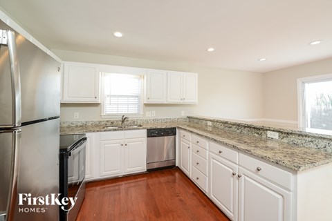 A kitchen with white cabinets and a granite countertop.