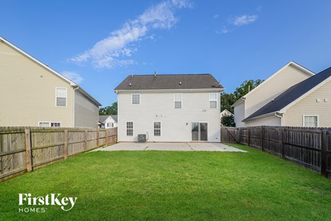 A house with a fence and a grassy yard is shown.