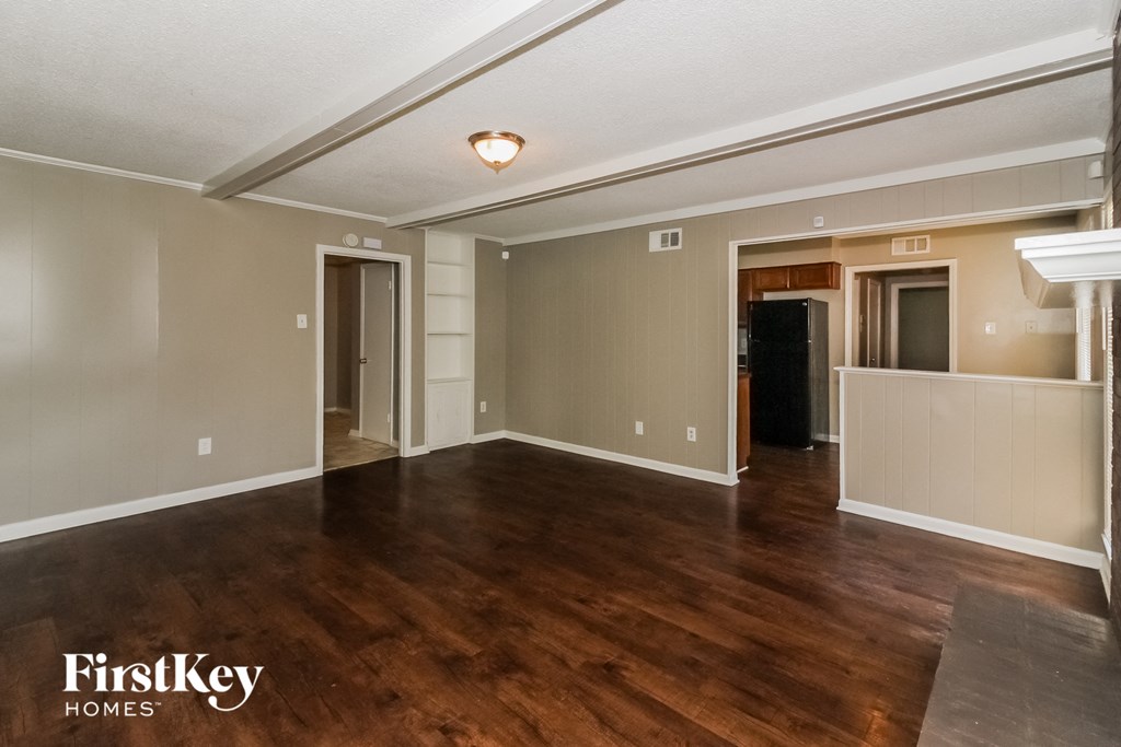 the living room and dining room of an empty house with wood flooring