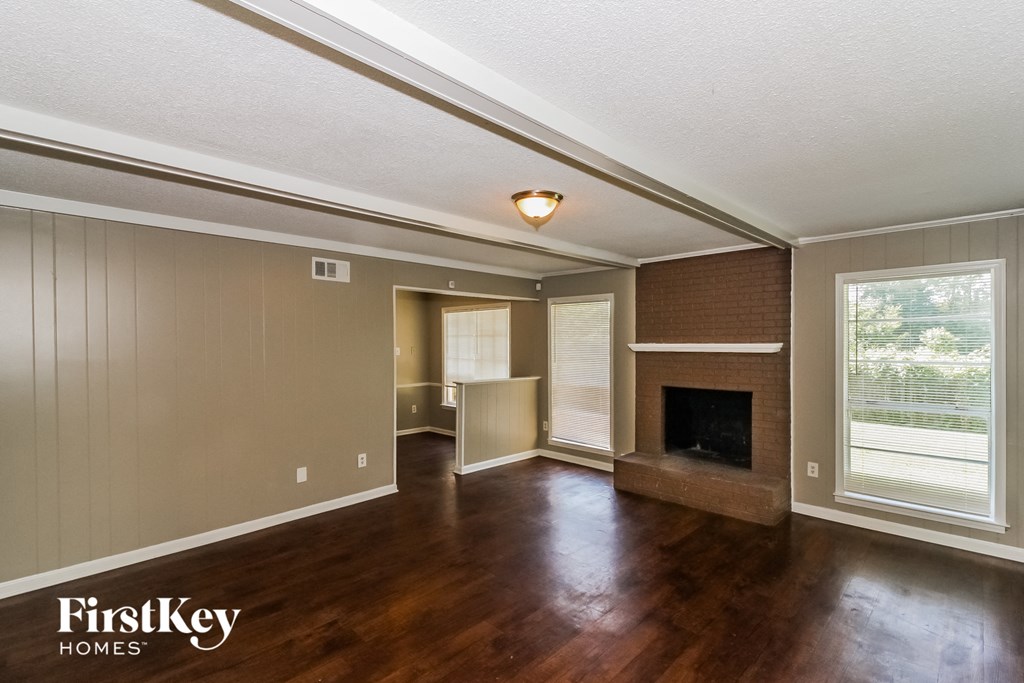 the living room and dining room of a house with wood flooring and a fireplace