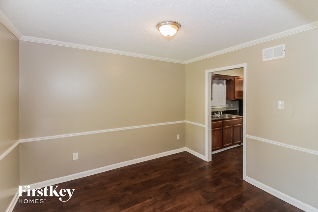 the living room and dining room of a house with wood flooring and a doorway