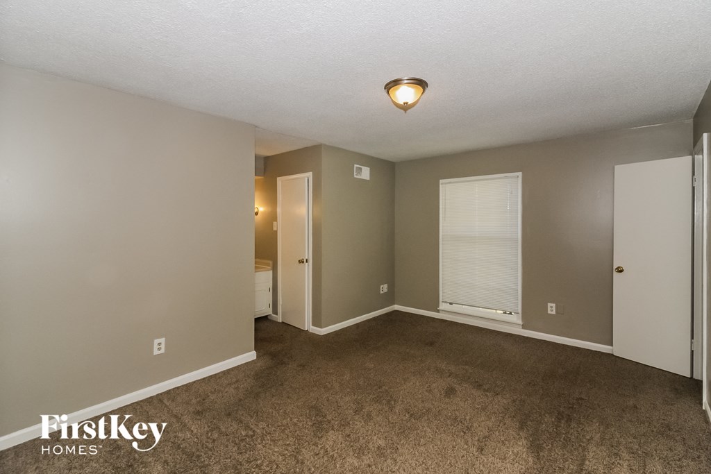 an empty living room with carpet and a door to a bathroom