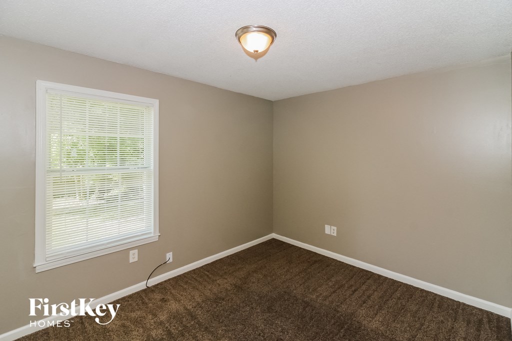 a bedroom with a brown carpet and a large window
