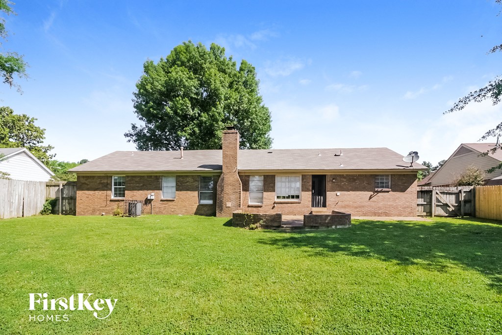 a brick house with a grassy yard and a tree