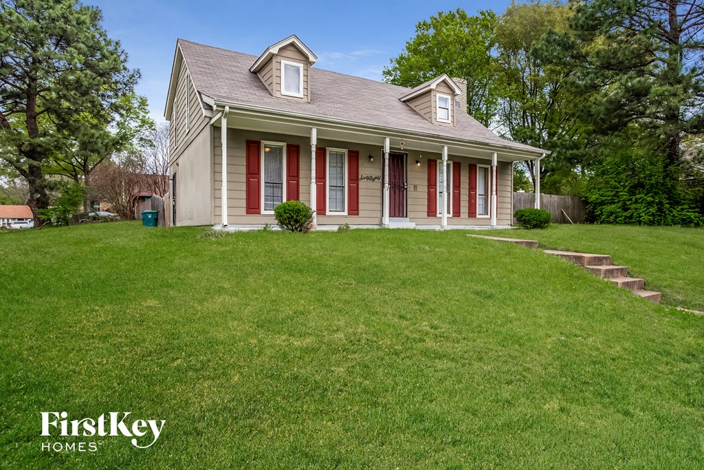 a white house with red shutters and a lawn
