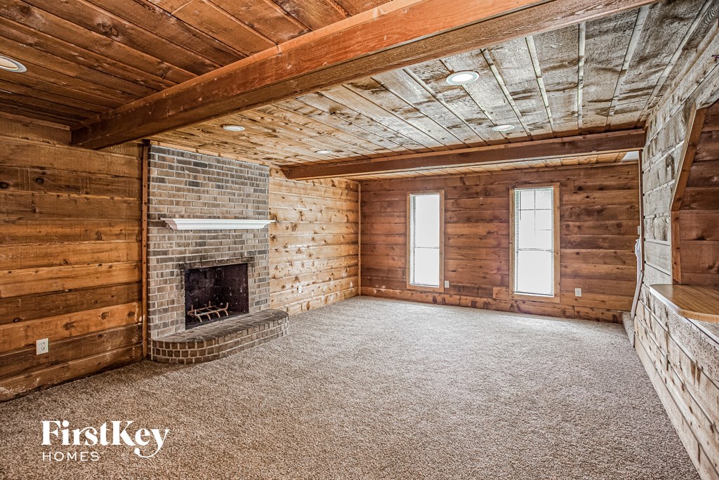 a living room with a brick fireplace and wooden walls