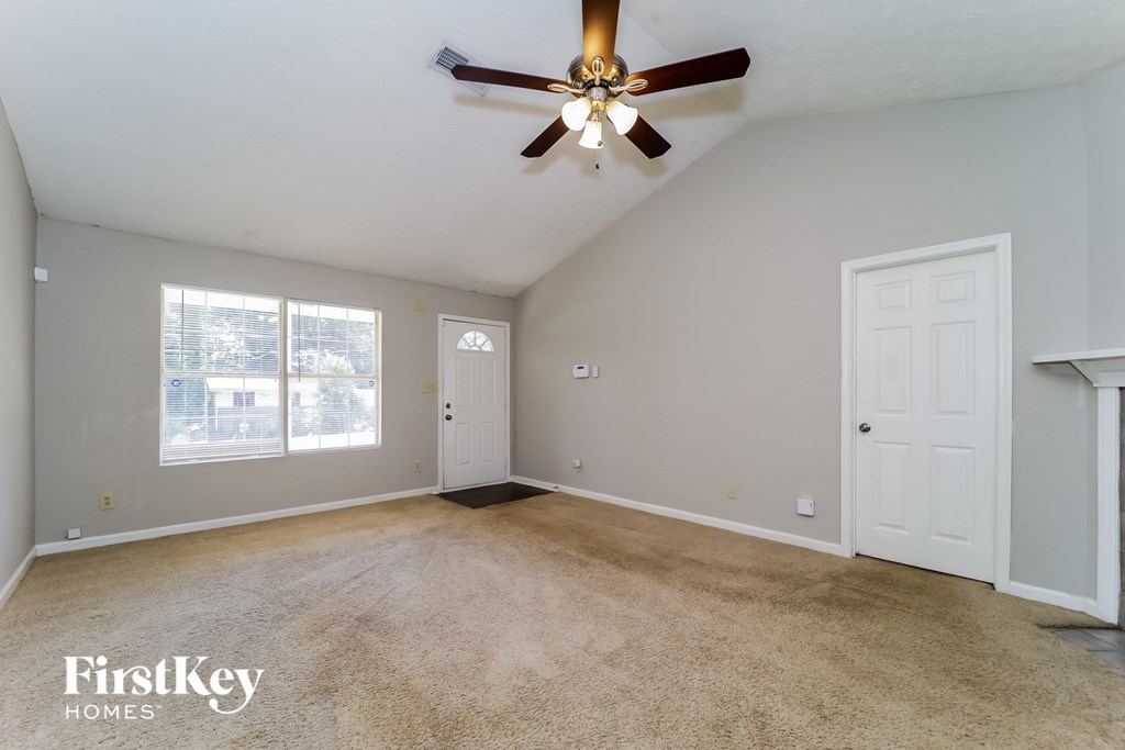 A spacious room with a ceiling fan and two doors.