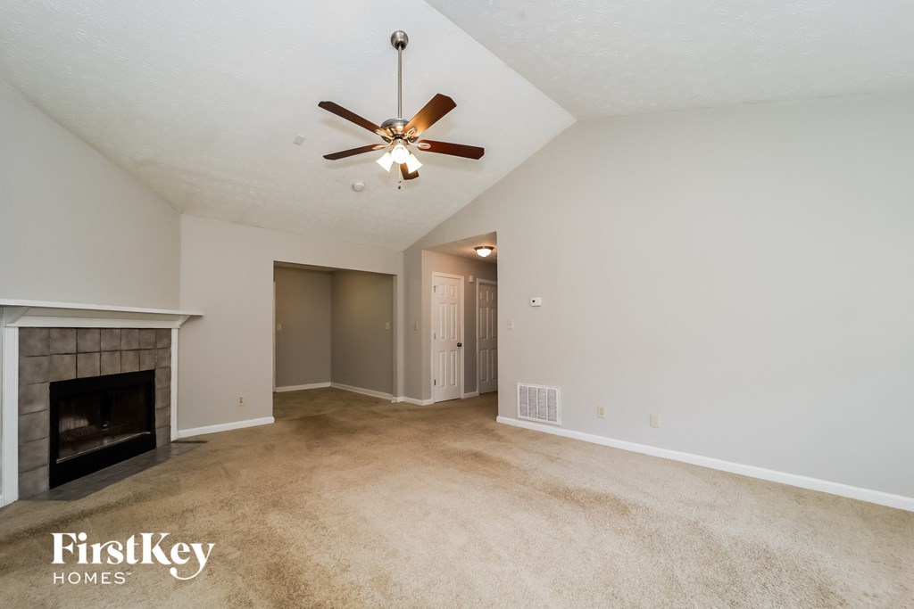 A spacious room with a fireplace and a ceiling fan.