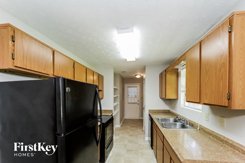 A kitchen with a black refrigerator and wooden cabinets.