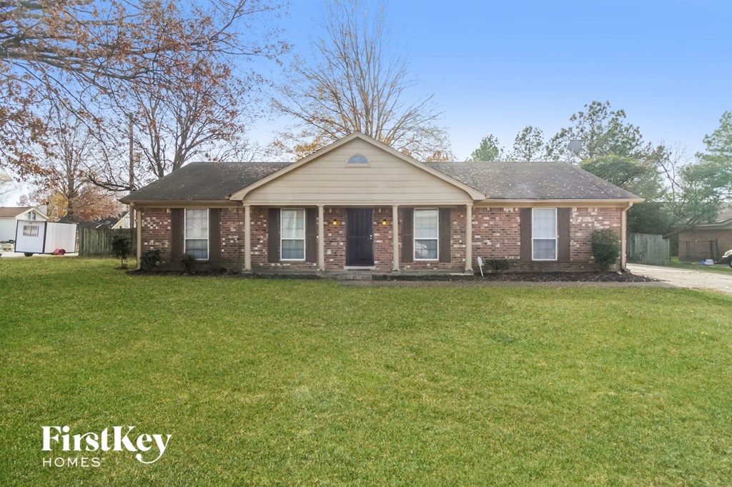 A brick house with a grassy front yard.