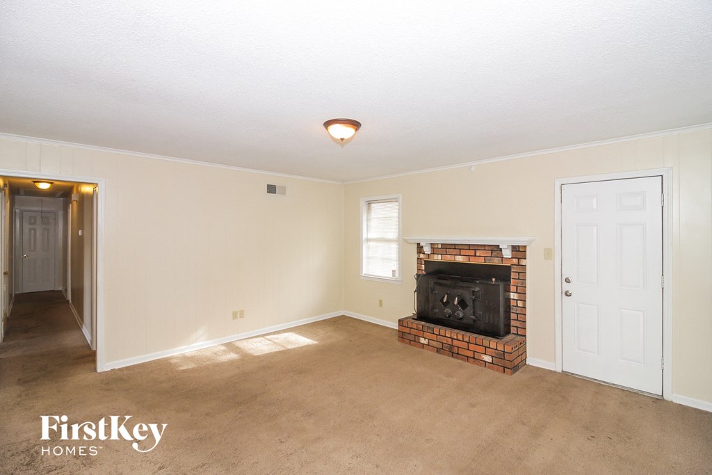 A living room with a fireplace and a door on the left.
