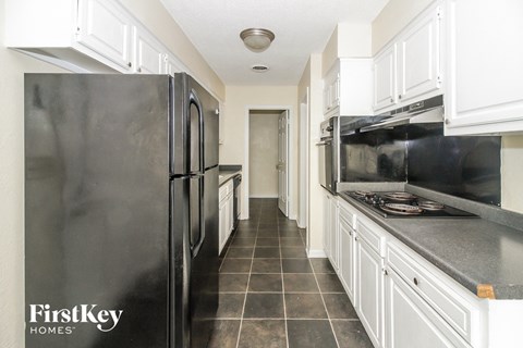 A kitchen with a black refrigerator and white cabinets.