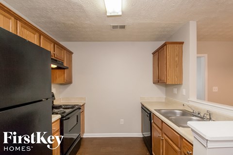 A kitchen with wooden cabinets and a black refrigerator.