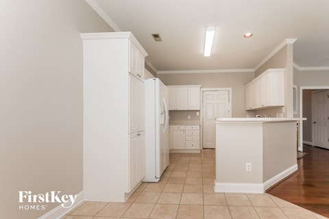 A kitchen with white cabinets and a white island.