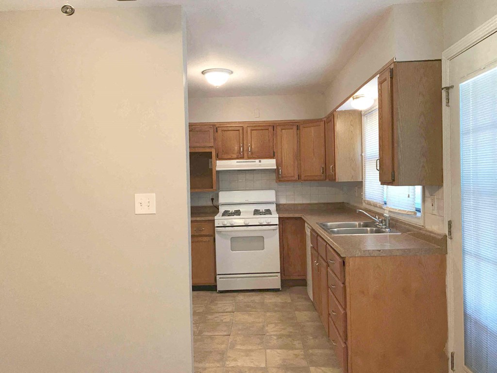 an empty kitchen with wooden cabinets and white appliances
