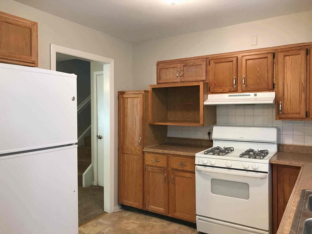 a kitchen with wooden cabinets and a white stove and refrigerator