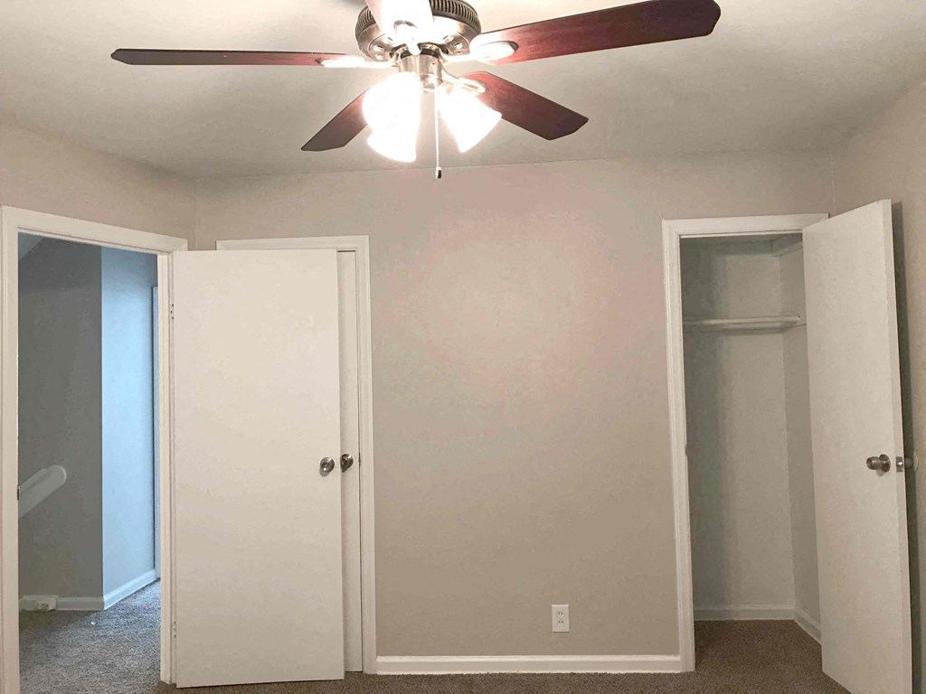 a bedroom with a ceiling fan and a closet