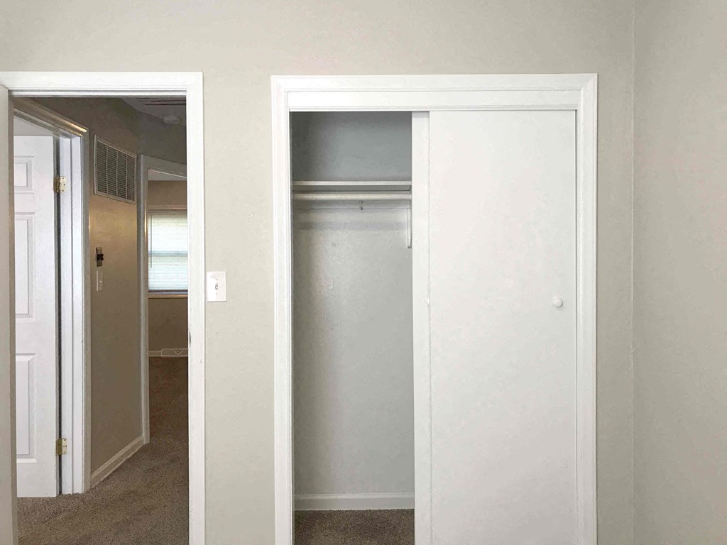an empty closet with a door open to a hallway and a door to a bedroom