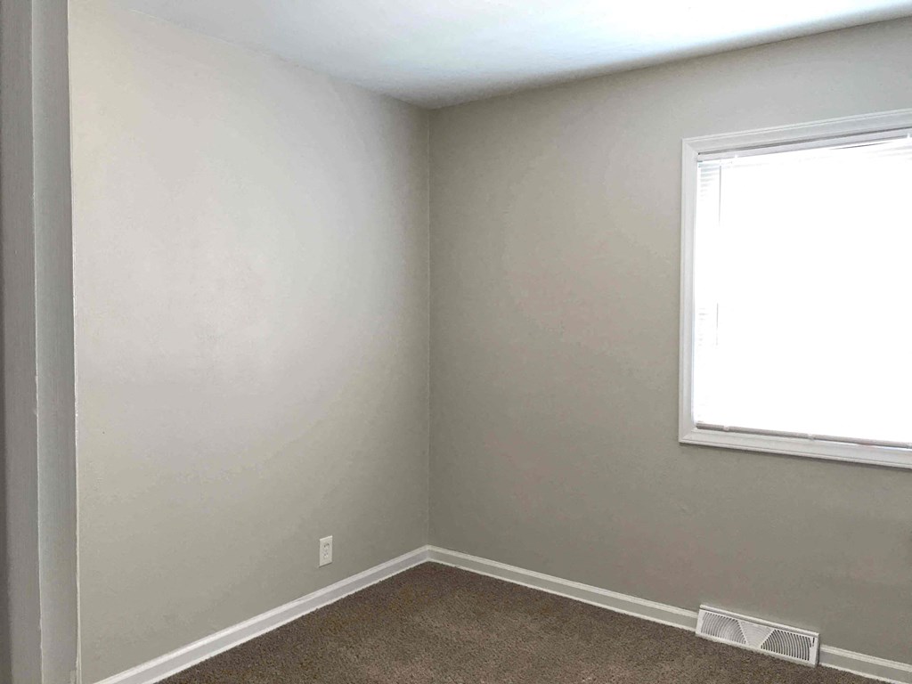 an empty room with a window and a carpet