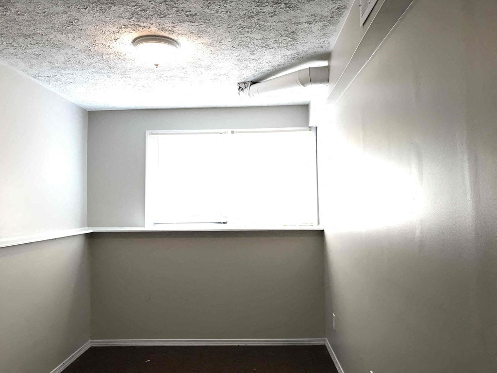 an empty room with a window and a light on the ceiling
