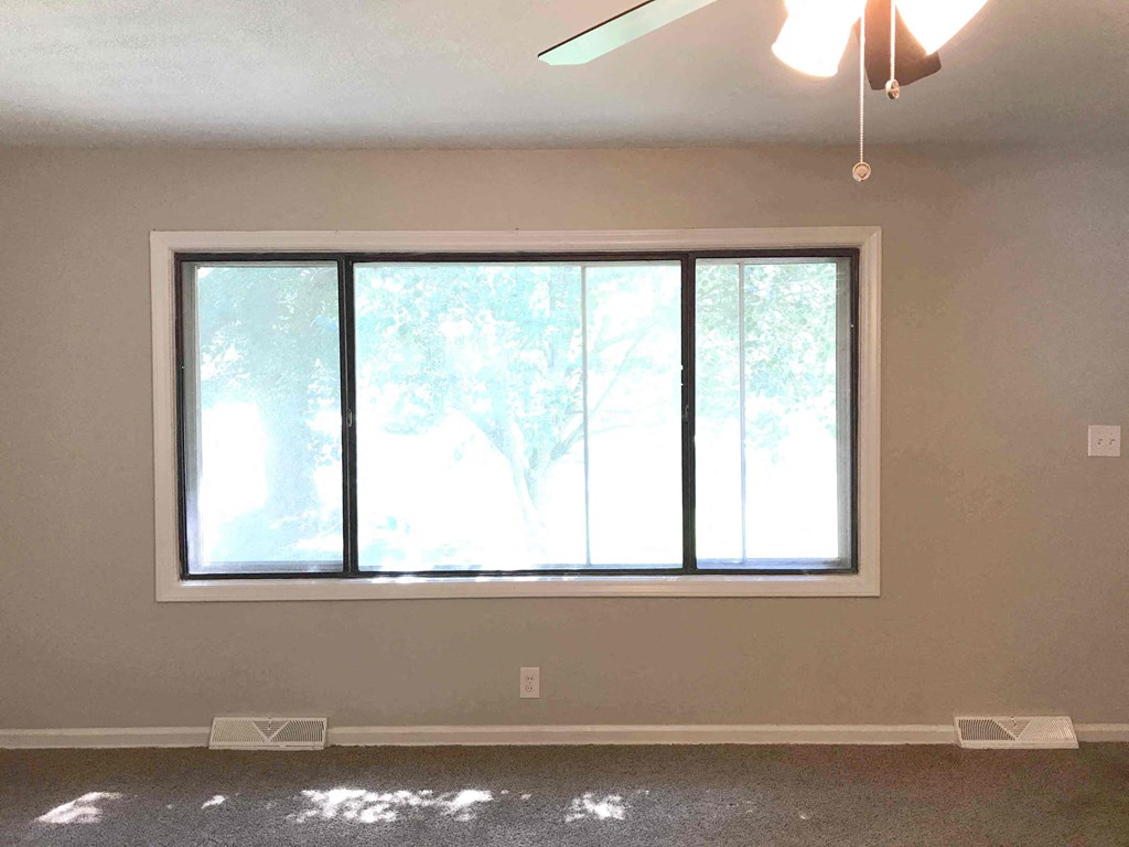 a living room with a large window and a ceiling fan