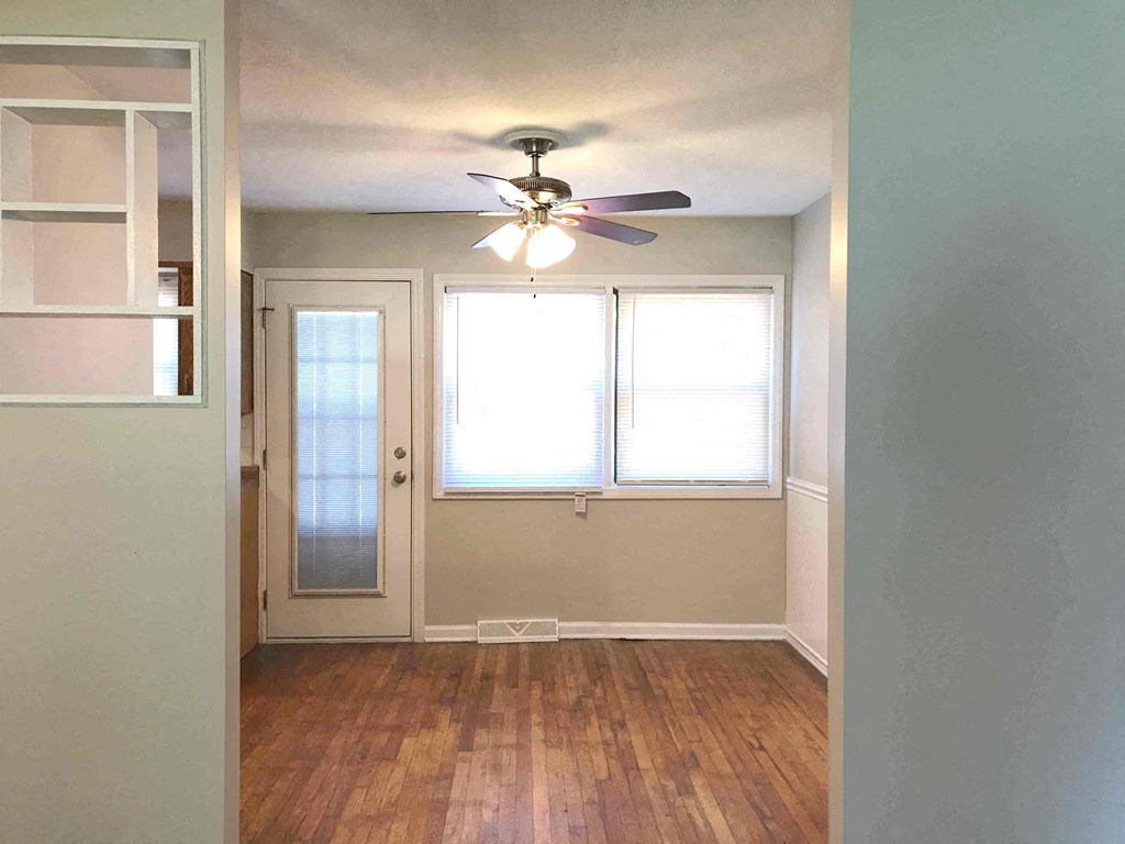 an empty room with a ceiling fan and two windows