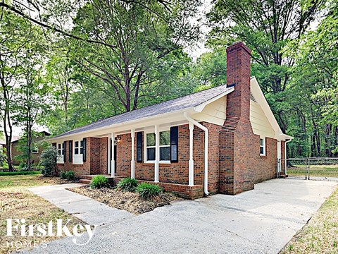 a small brick house with a chimney and a sidewalk
