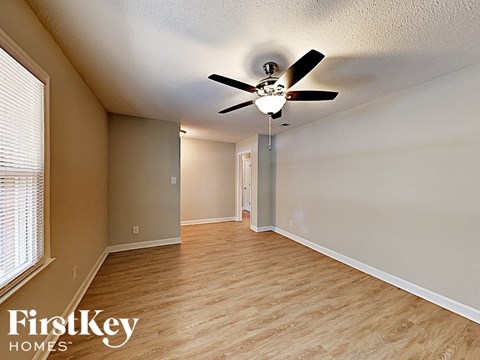 an empty living room with a ceiling fan and a window